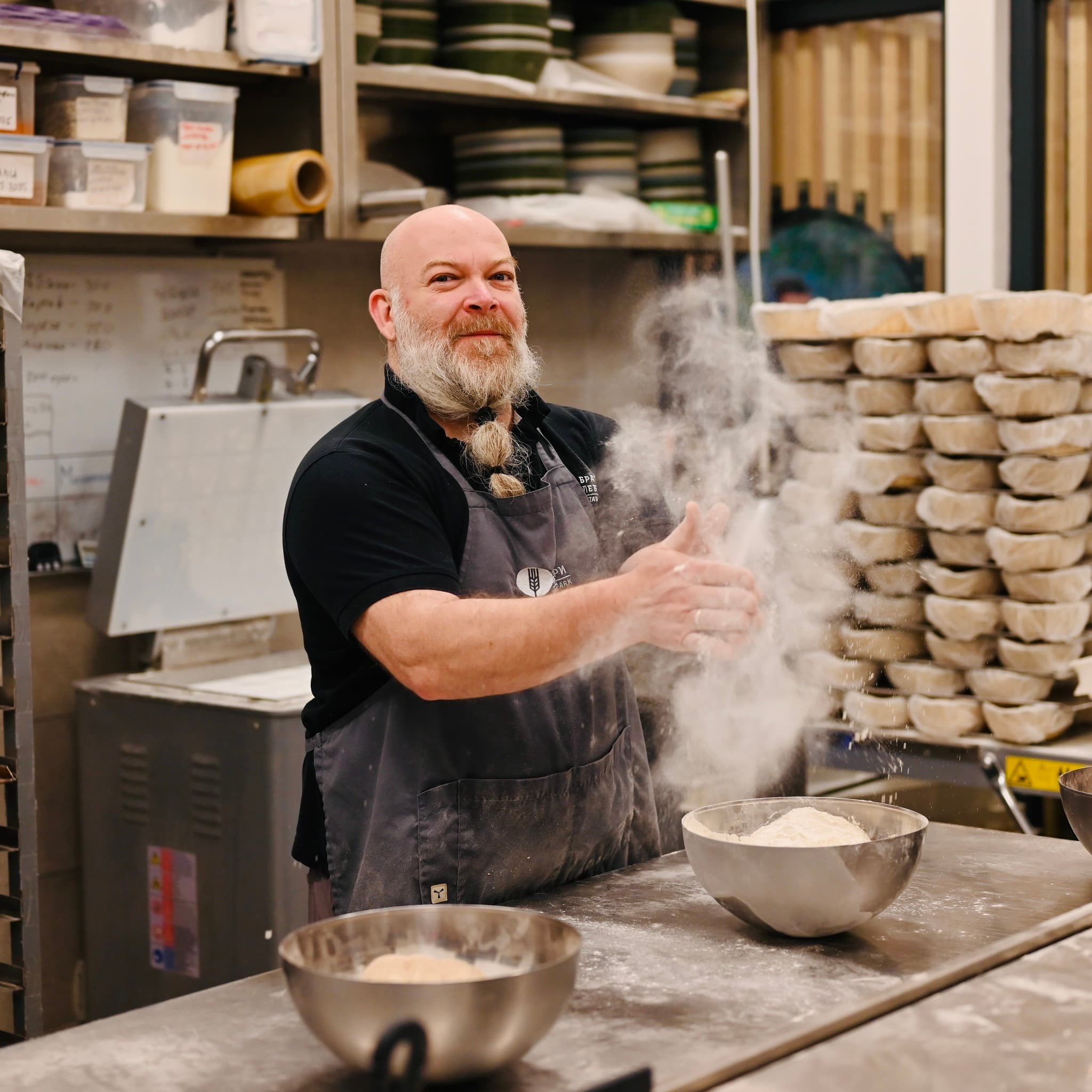 Пекар на работната маса с брашно във въздуха